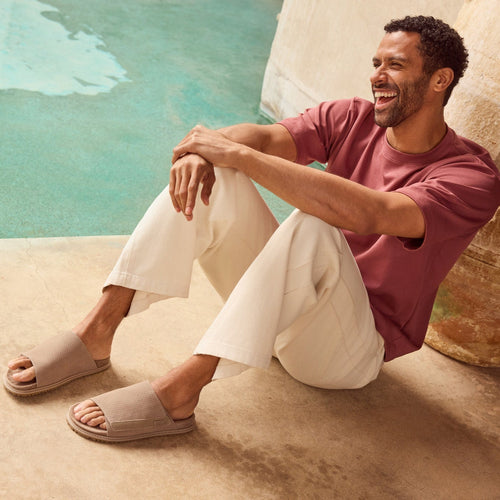 Danilo Adjustable slide sandal in dune perf on model sitting poolside